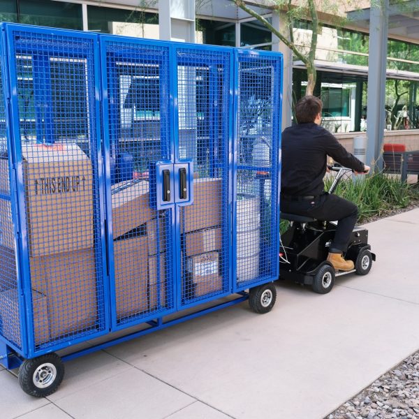 A man pulling a locking cage cart in a warehouse or storage area.